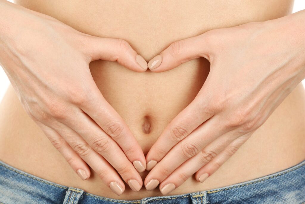 Person forming a heart shape with their hands over their stomach, representing digestive health