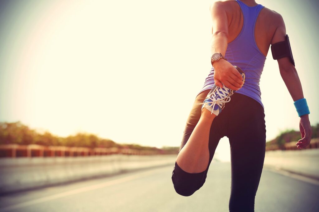 Runner stretching at sunrise, representing NOW Sports nutrition