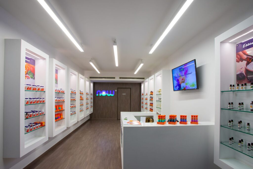 Backlit display shelving inside the NOW Supplements Store, stocked with the full NOW Foods range